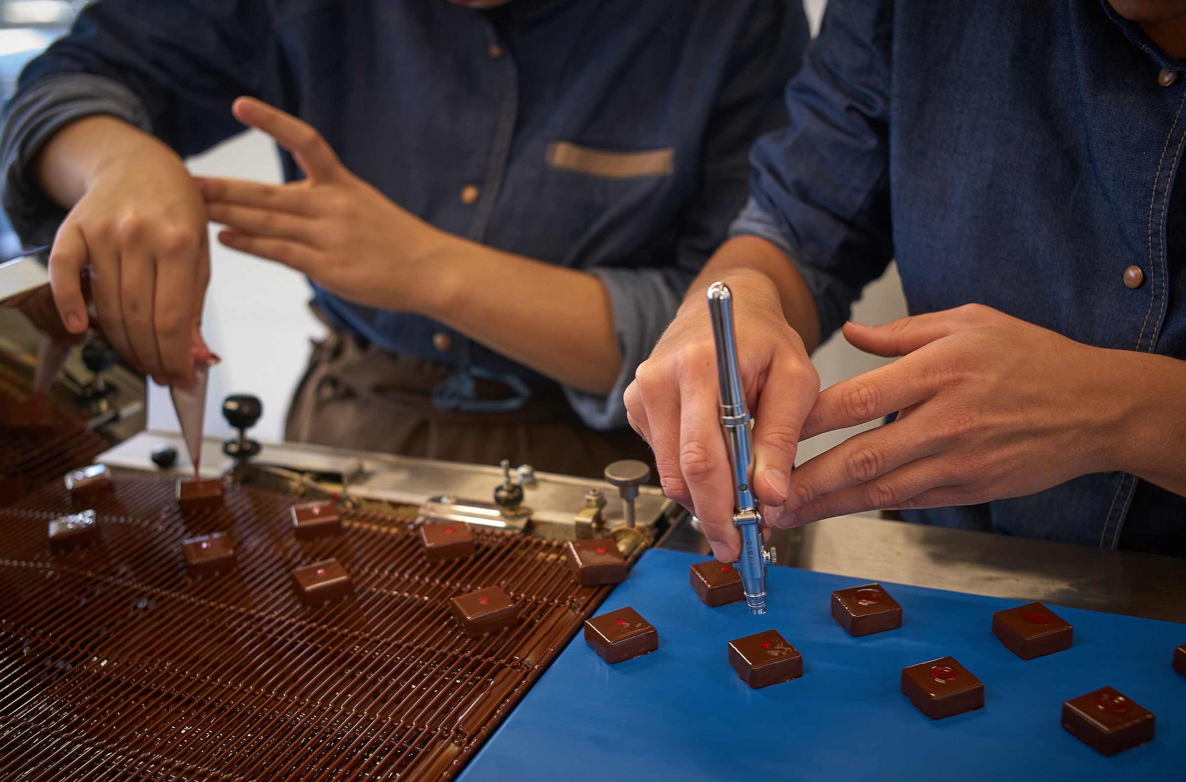 Deux chocolatiers décorant des ganaches à la main dans l’atelier