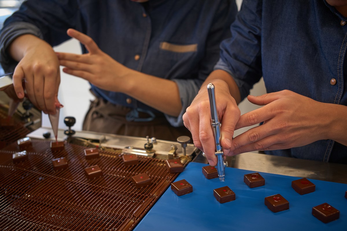 Deux chocolatiers décorant des ganaches à la main dans l’atelier
